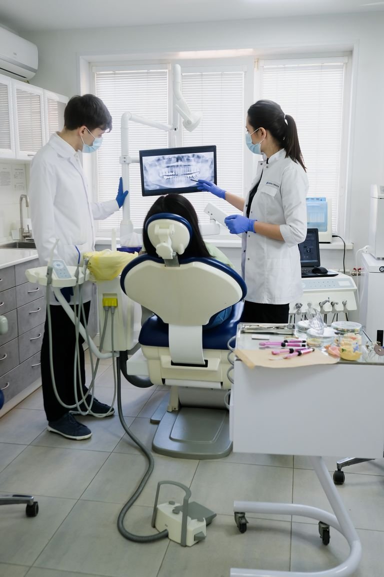 Professional dental team examining patient with advanced equipment in a modern clinic.