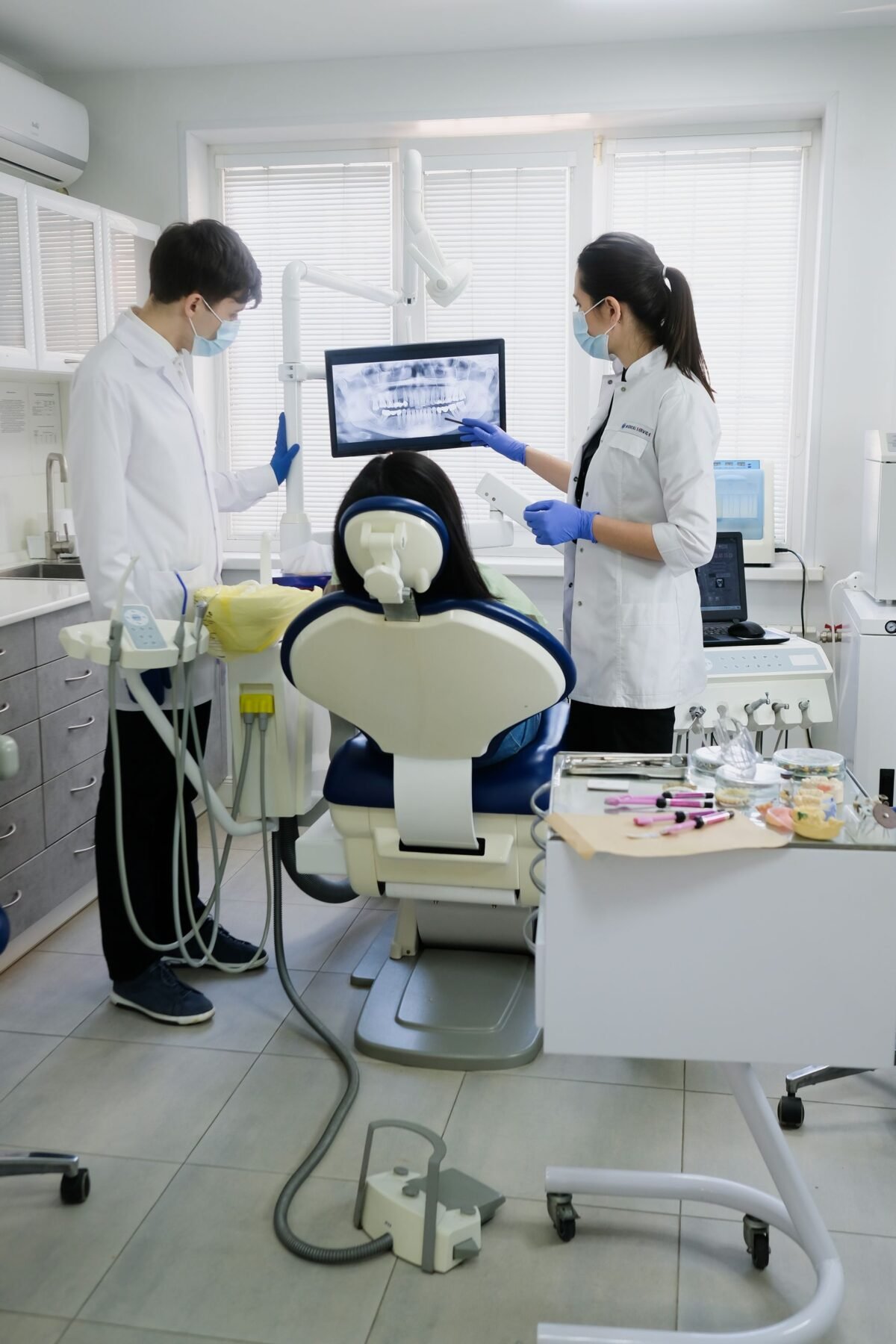 Professional dental team examining patient with advanced equipment in a modern clinic.